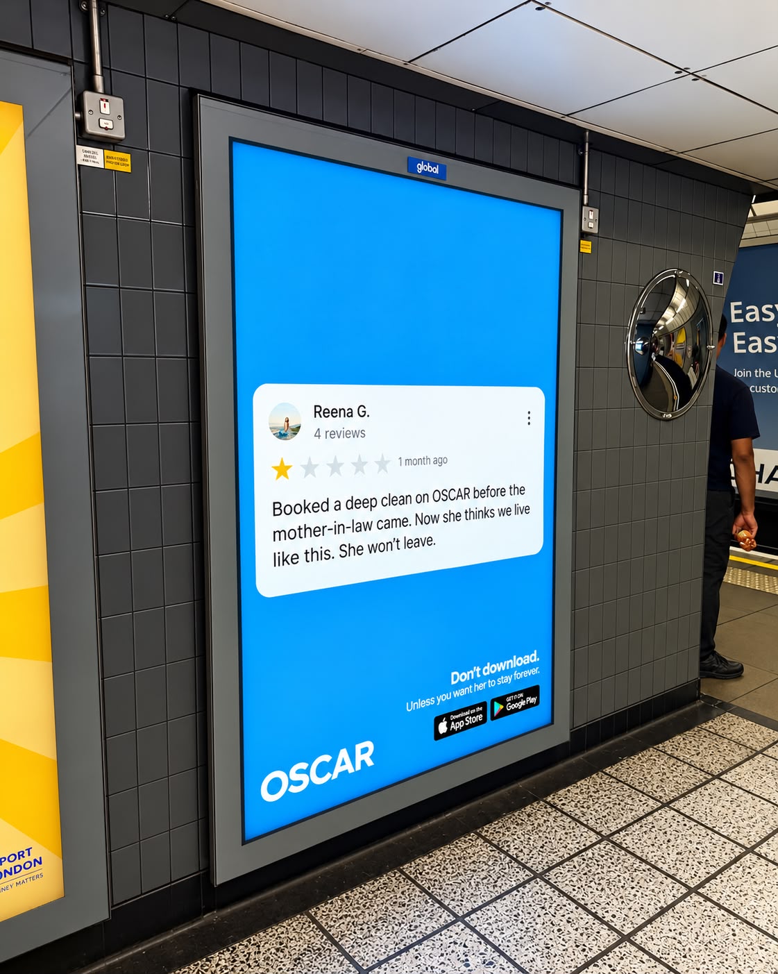 OSCAR digital platform panel inside a London Underground station, showing reviewer Reena G. and the line 'Don't download. Unless you want her to stay forever.'