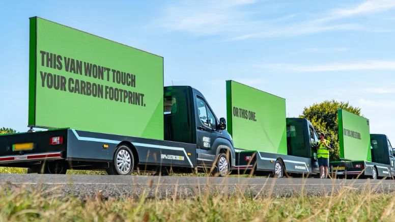 A convoy of green digital AdVans on a UK road