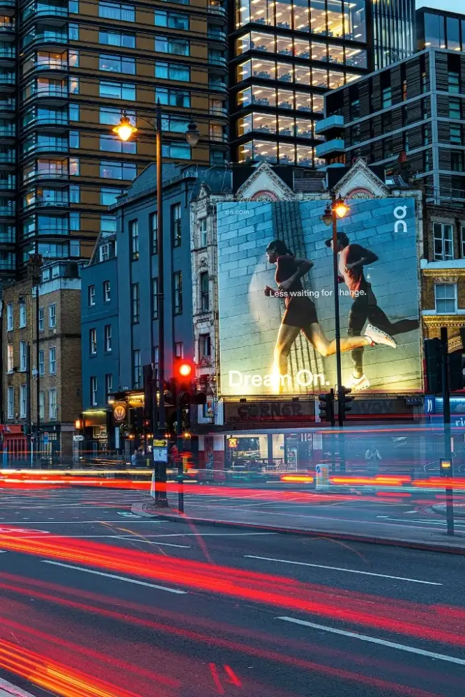A roadside digital billboard on a London street at night